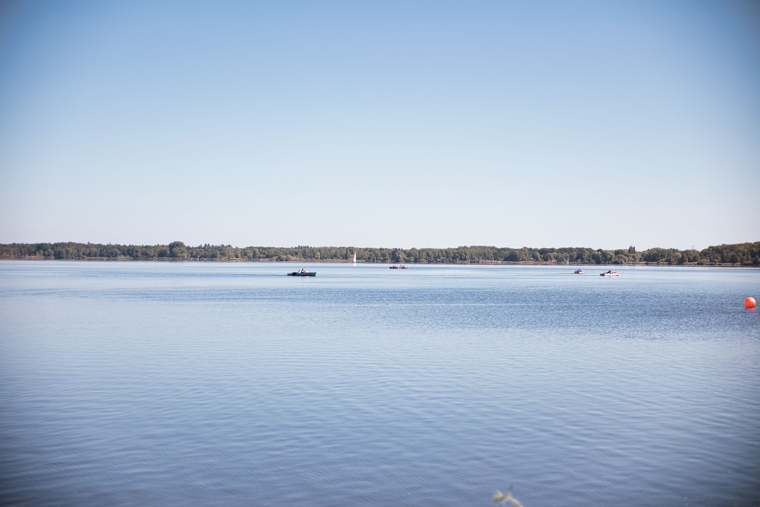 A calm lake with boats and a distant shoreline.