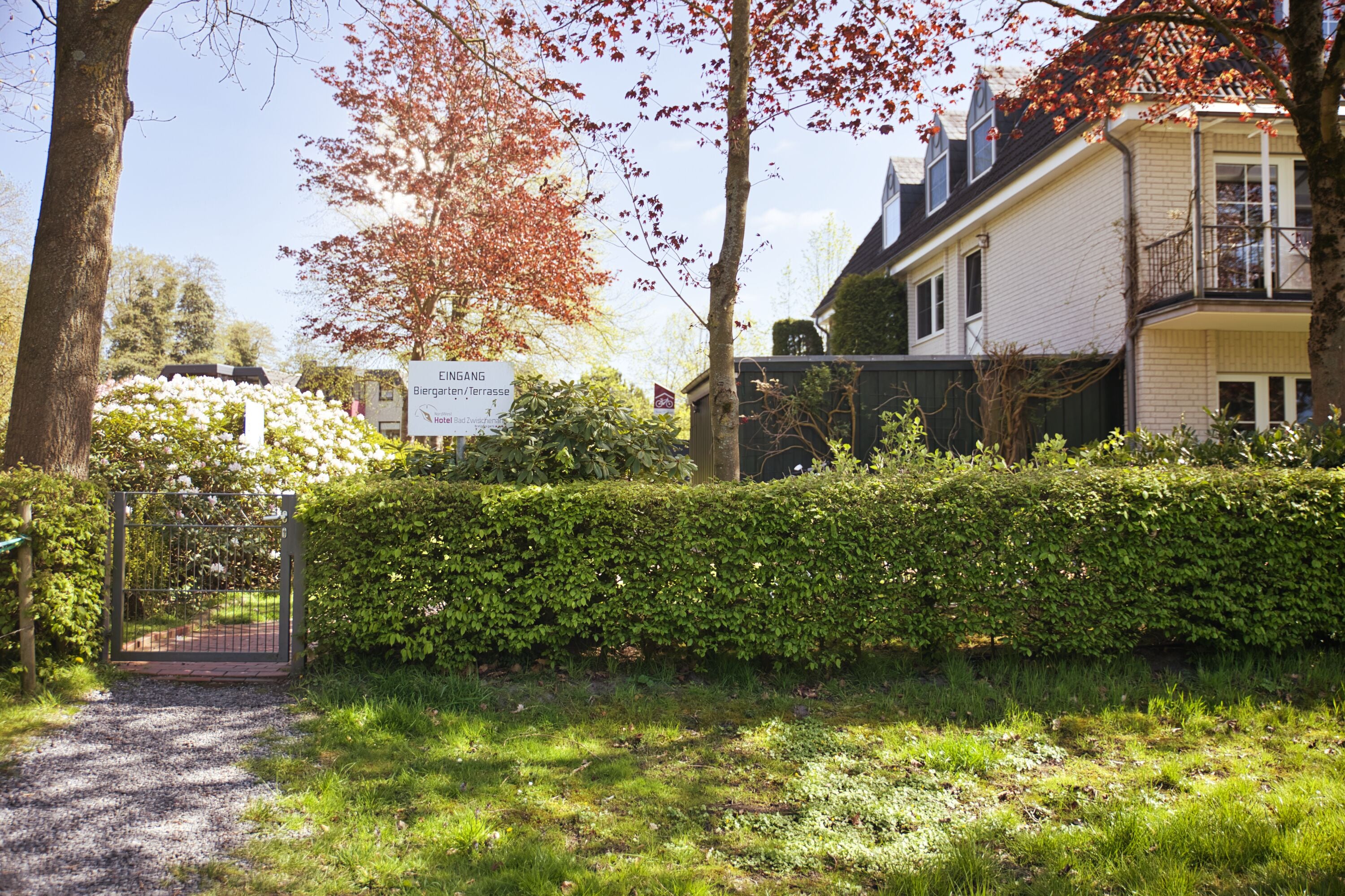 A gated entrance to a residential area with a sign indicating 'Eingang' and 'Biergarten/terrasse.'