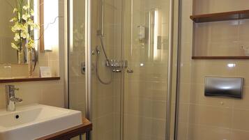 Ein modernes Badezimmer mit einer einteiligen Duschkabine, einem weißen Waschbecken und einer Toilette.