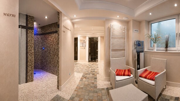 Un área de spa con pared de mosaicos, fuente de agua y asientos con vistas al exterior.