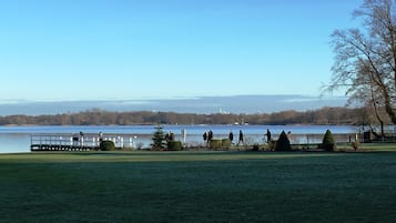 Un parque junto al lago con césped, un muelle de madera y una fila de árboles.