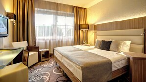 Una habitación de hotel con una cama grande, un escritorio, una silla y un televisor.
