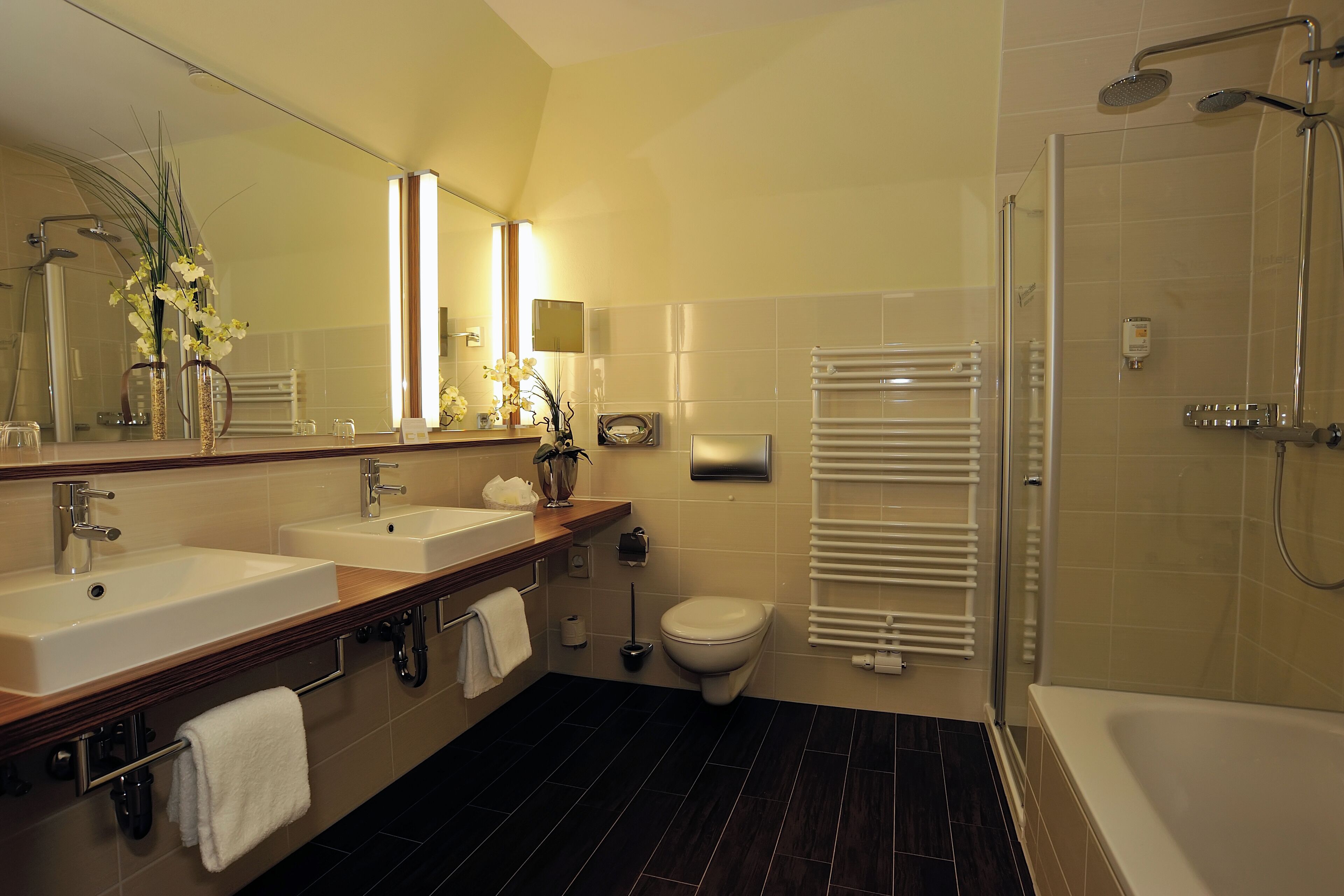 Un baño moderno con dos lavamanos, inodoro, bañera y ducha.