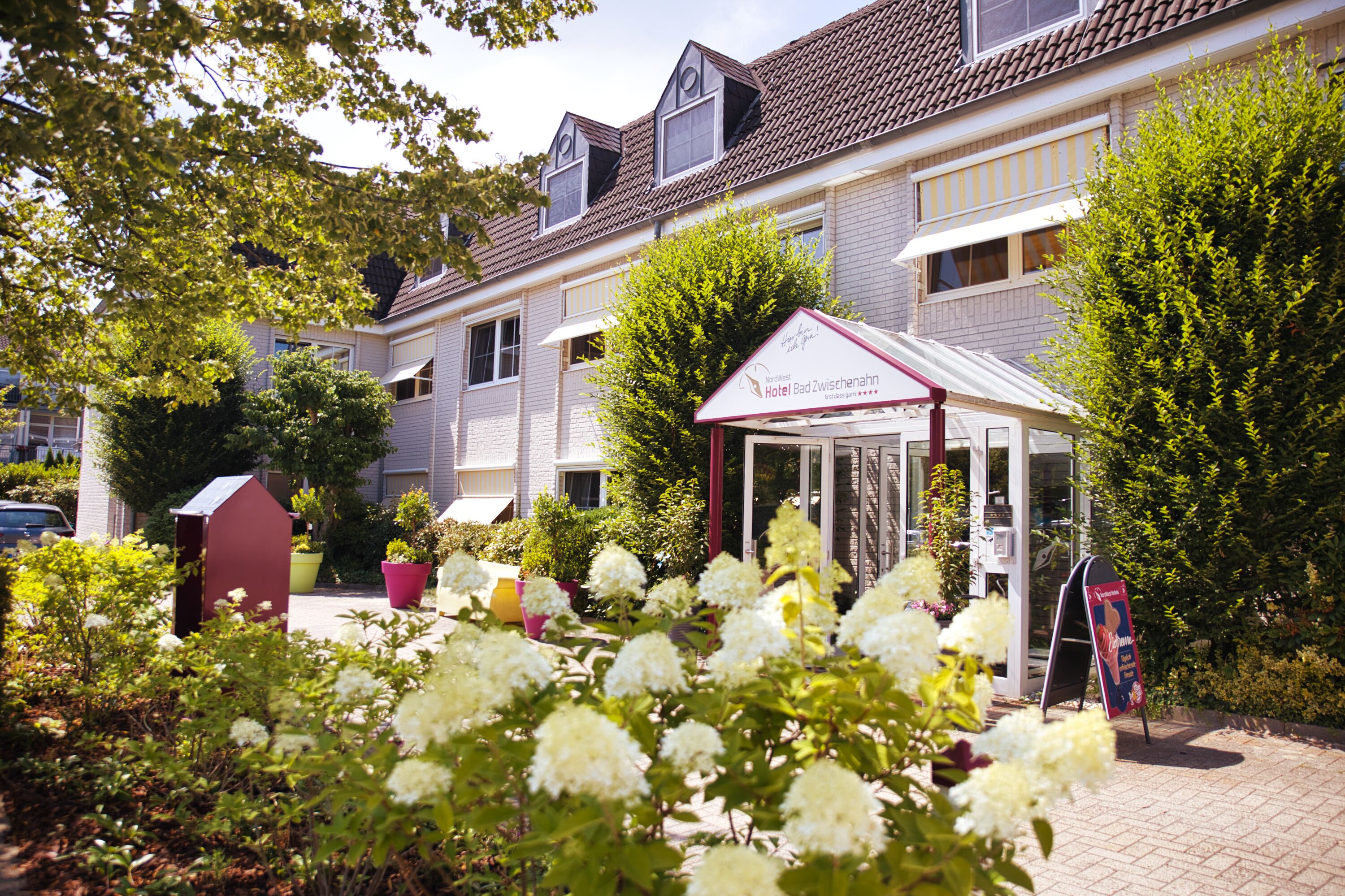 A hotel with a garden, a red and white marquee, and a brick facade.