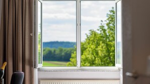 A window with a view of green trees and hills.