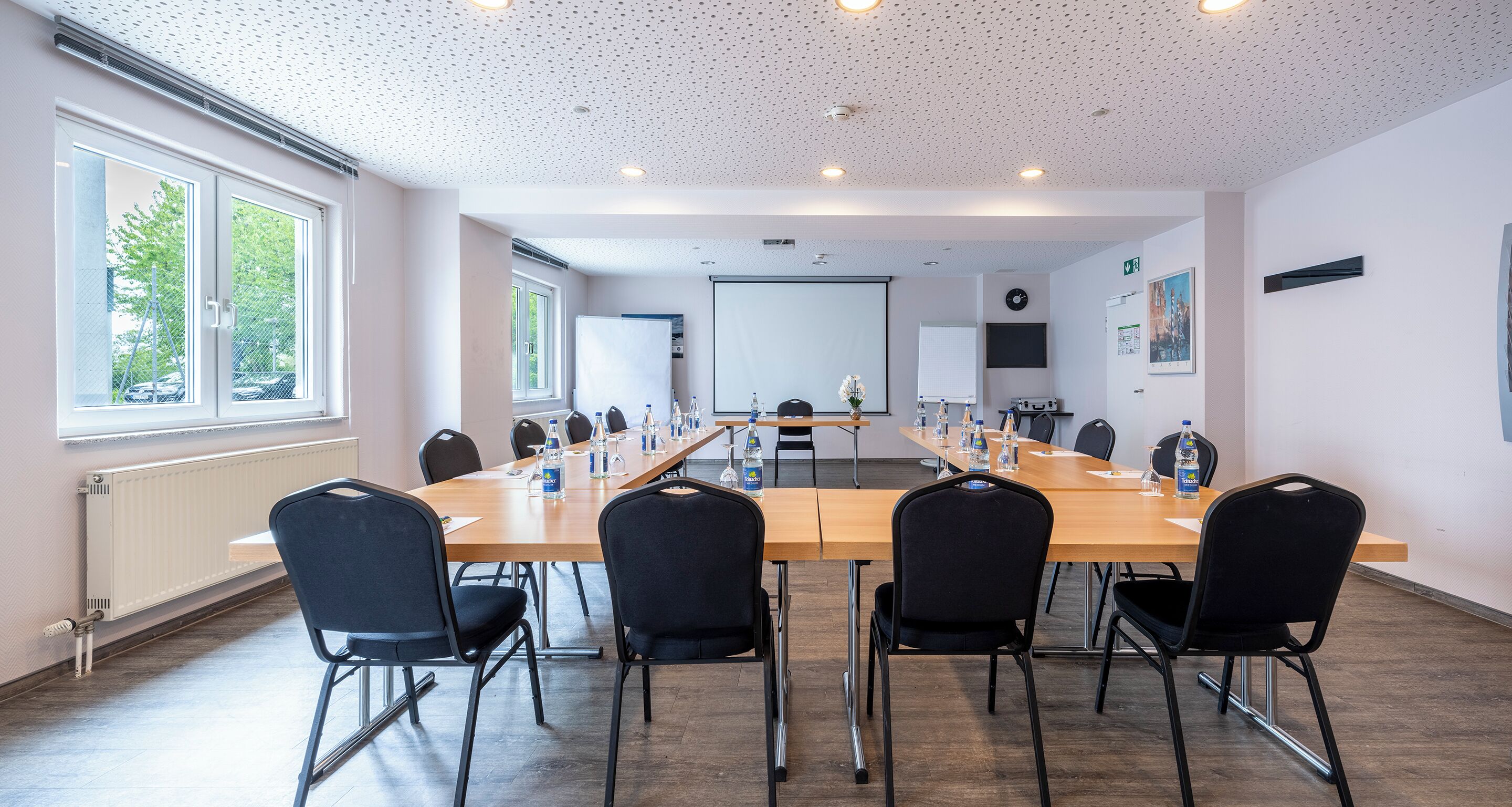 A conference room with a long table, chairs, and a projector screen.
