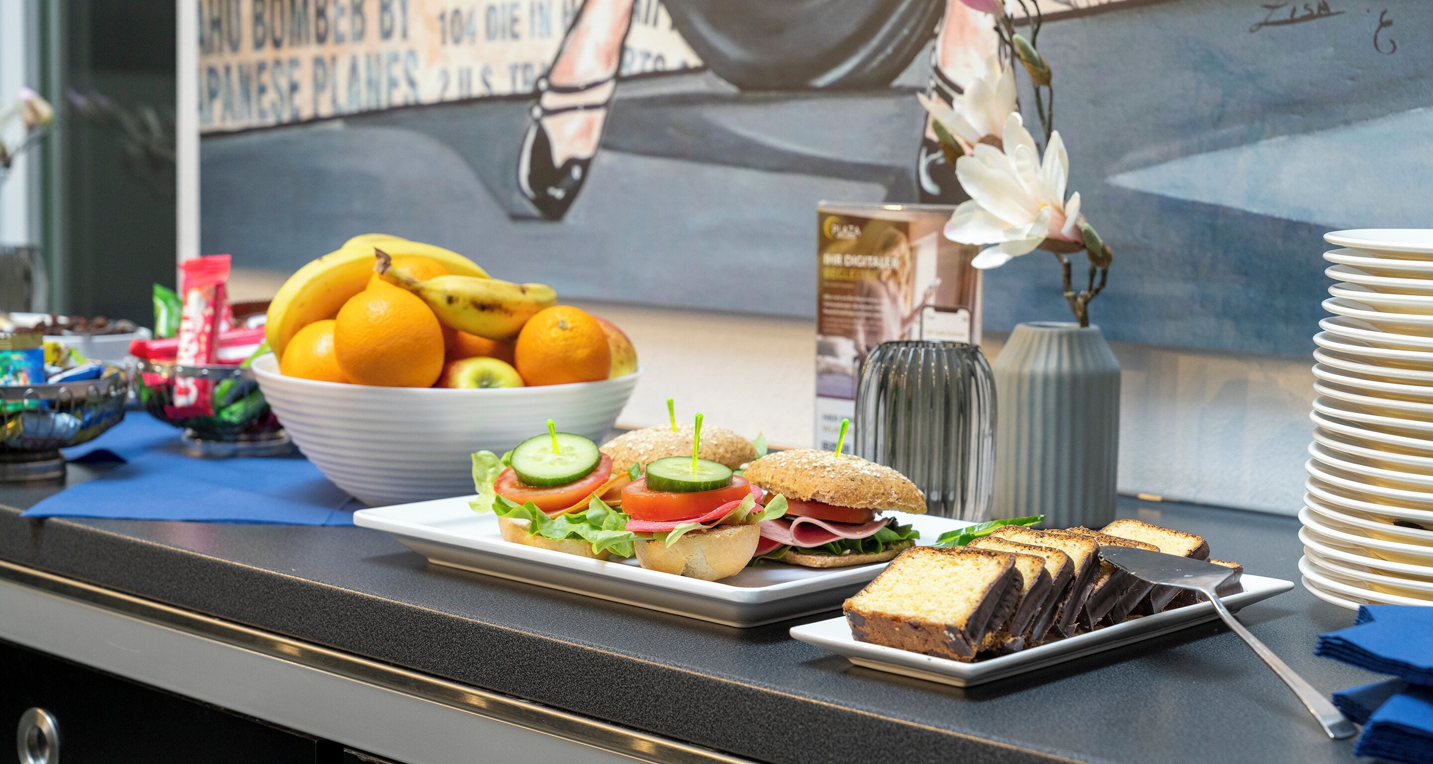 Une table de buffet avec des sandwichs, des fruits et un dessert au chocolat.