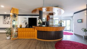 A reception area with a curved wooden counter, a large black door, and a BMZ machine.