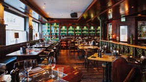 A restaurant with wooden tables and chairs, a bar area, and a display of bottles. - Der LIPPISCHE HOF (Bad Salzuflen)