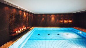 A modern indoor swimming pool with a tiled floor and a wall-mounted light fixture. - Der LIPPISCHE HOF (Bad Salzuflen)