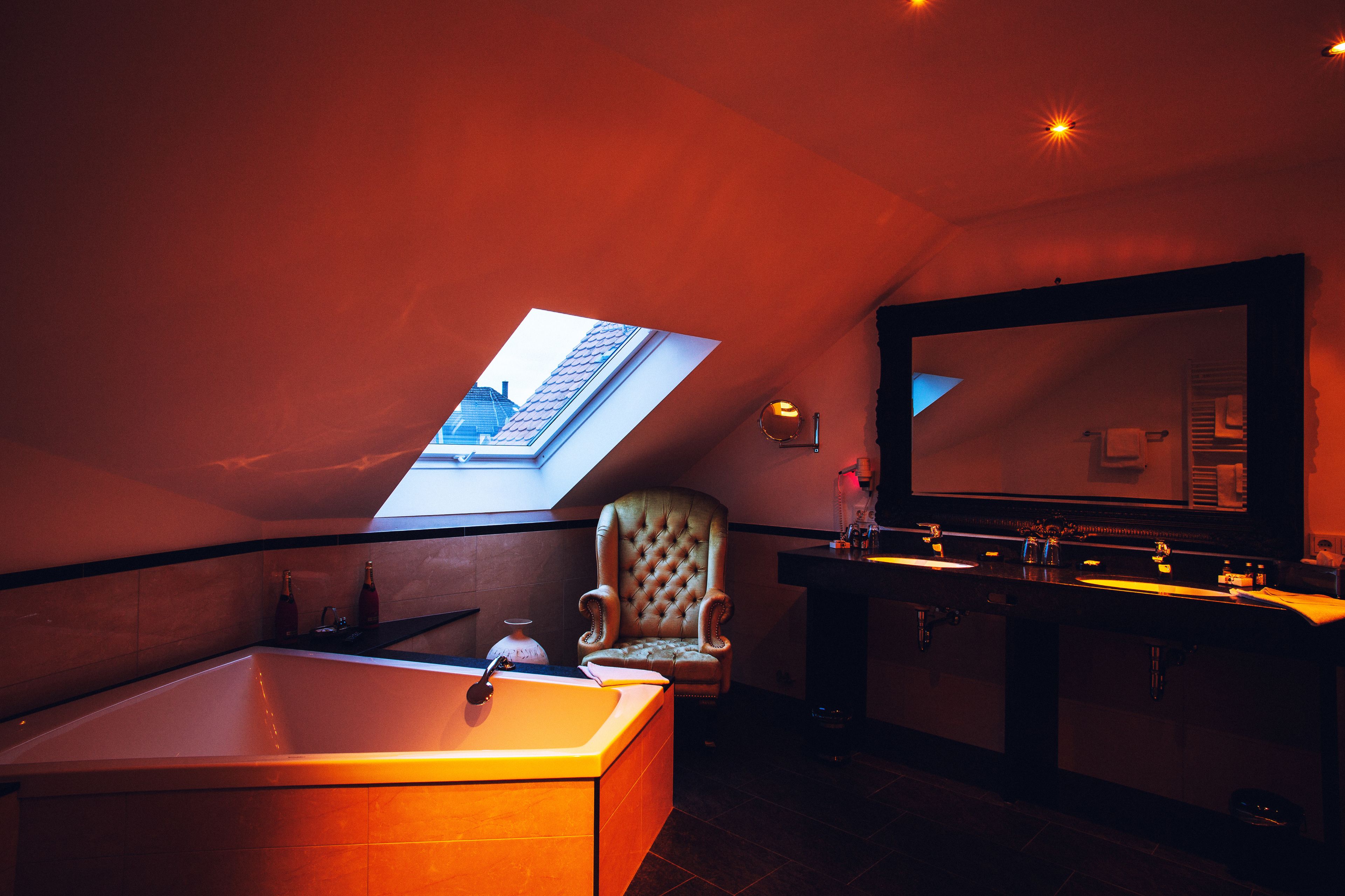 A bathroom with a skylight, a large mirror, a bathtub, and a vanity with a sink.