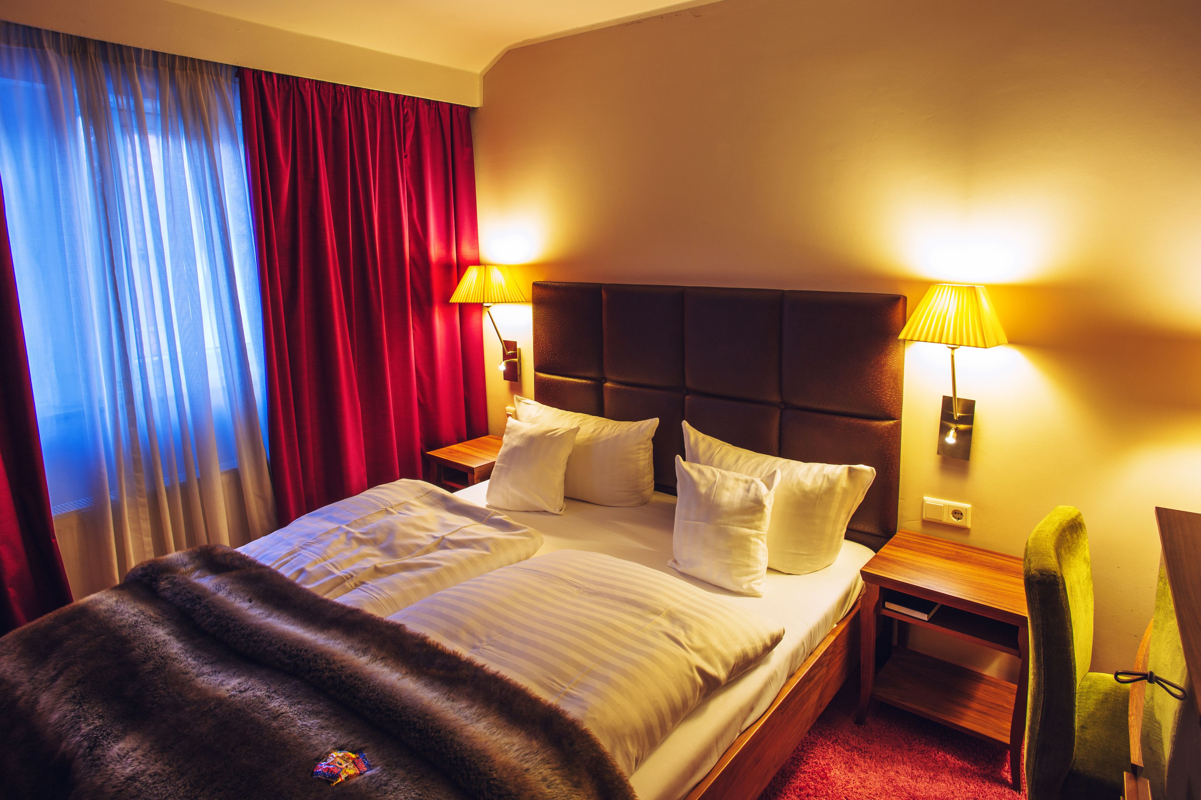 Ein Hotelzimmer mit einem großen Bett, zwei Nachttischen, einer Lampe und einem Sessel.