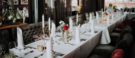 A long dining table set with white tablecloths, candles, and floral centerpieces.