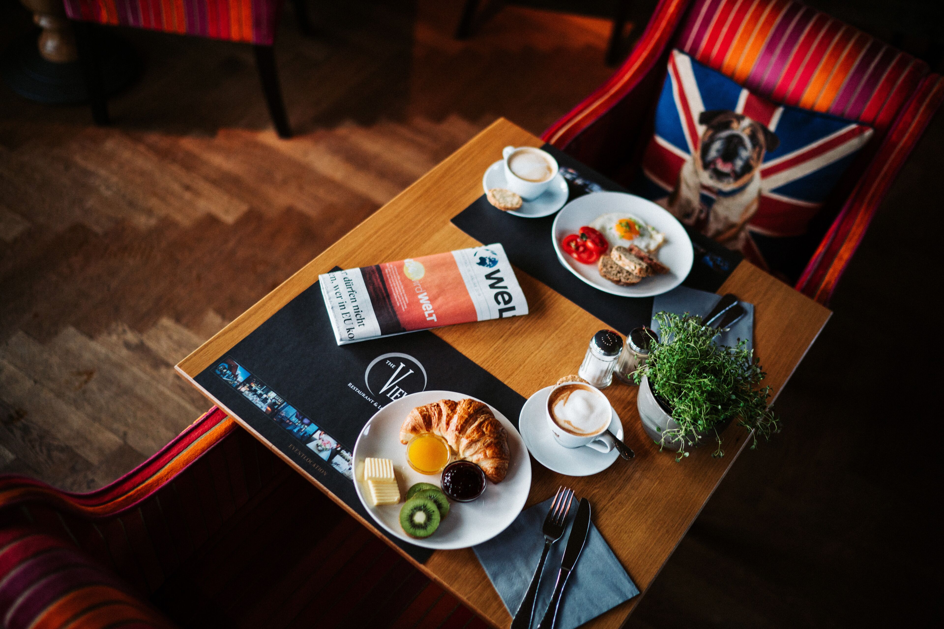 A breakfast table with croissants, fruit, coffee, and a menu.
