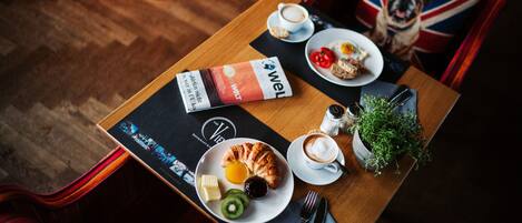 A breakfast table with croissants, fruit, coffee, and a menu.