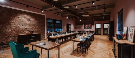 A spacious conference room with a long table, multiple chairs, and a brick wall.