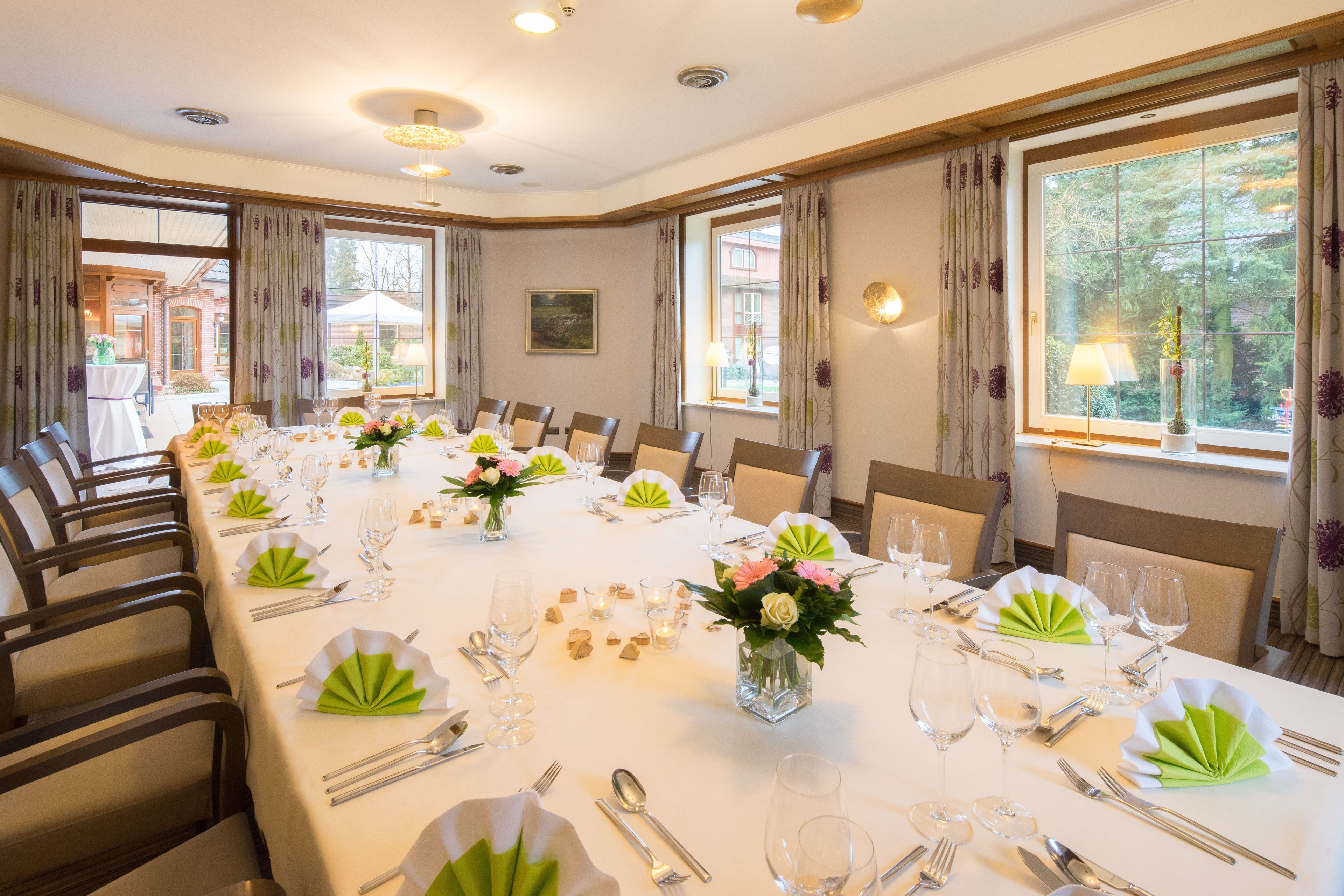 A long dining table set for a formal meal with chairs, candles, and floral centerpieces.