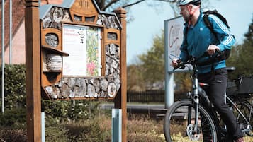 A wooden sign with text and a cyclist with a bicycle.