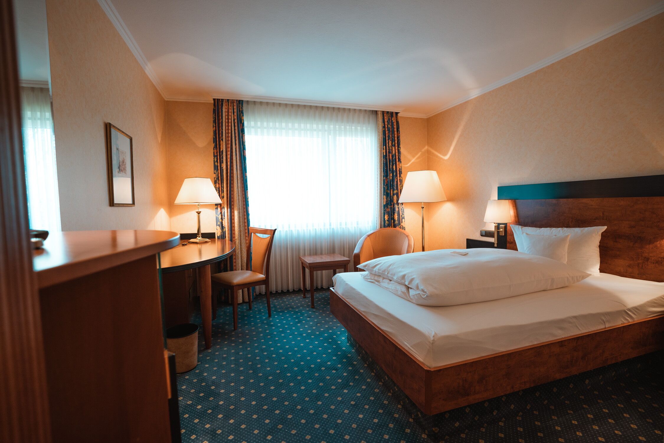 Una habitación de hotel con una cama, dos sillones, un escritorio y dos lámparas.