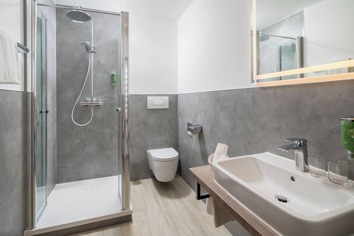A modern bathroom with a glass-enclosed shower, a white sink, and a mirror above the sink.