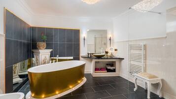 A modern bathroom with a freestanding bathtub, a vanity with a mirror, and a white bench.