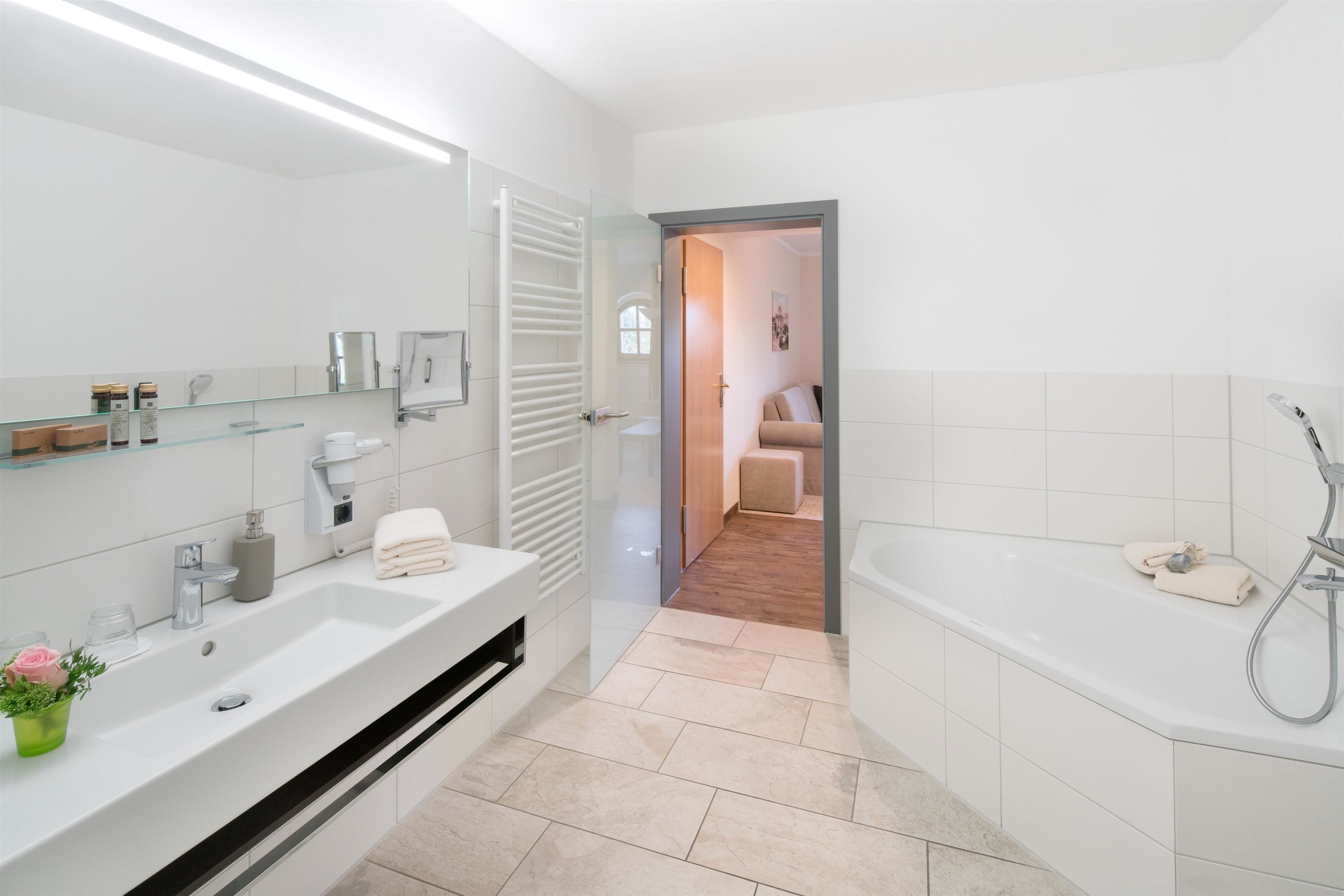 Un baño moderno con un lavamanos grande, espejo y bañera.
