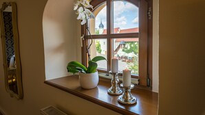 A window with a view of a town, a potted plant, and two candles on a wooden ledge. - Wasserschloss Klaffenbach Schlosshotel (Chemnitz)