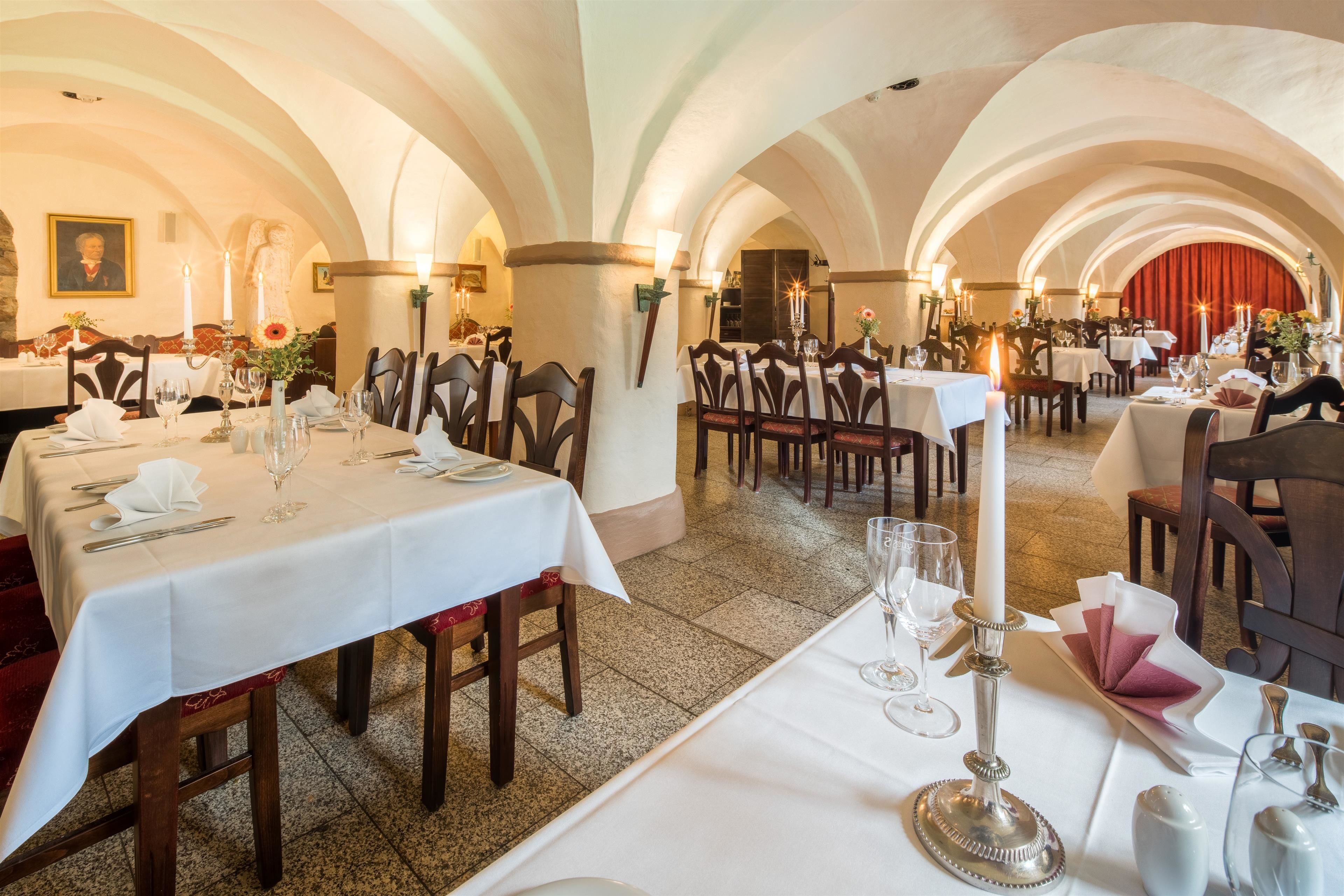 A restaurant with multiple tables set for dining, featuring white tablecloths and candle centerpieces.