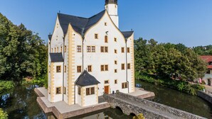 A historic building with a prominent tower, a stone bridge, and a river. - Wasserschloss Klaffenbach Schlosshotel (Chemnitz)