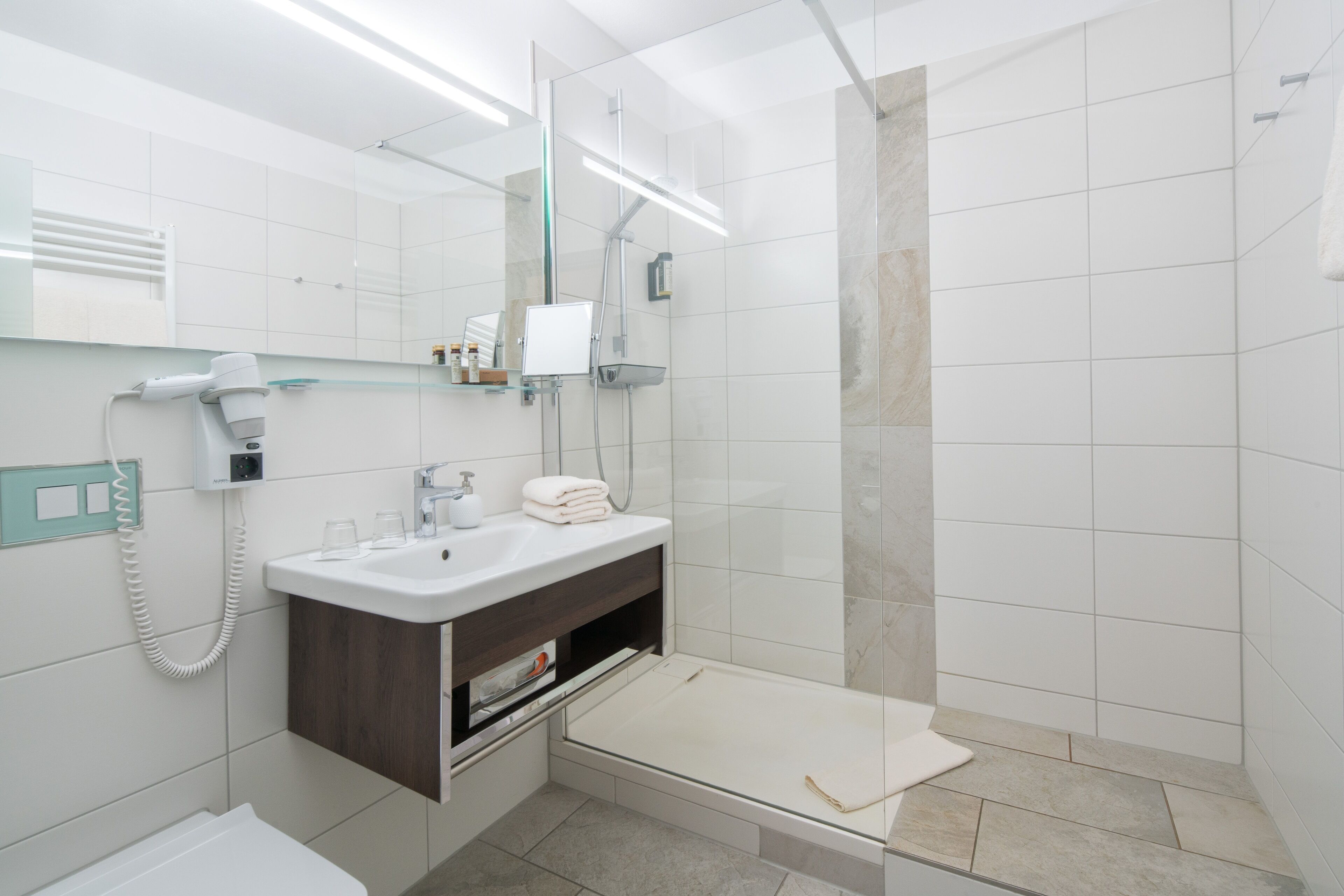 A modern bathroom with a shower, a sink, and a mirror.