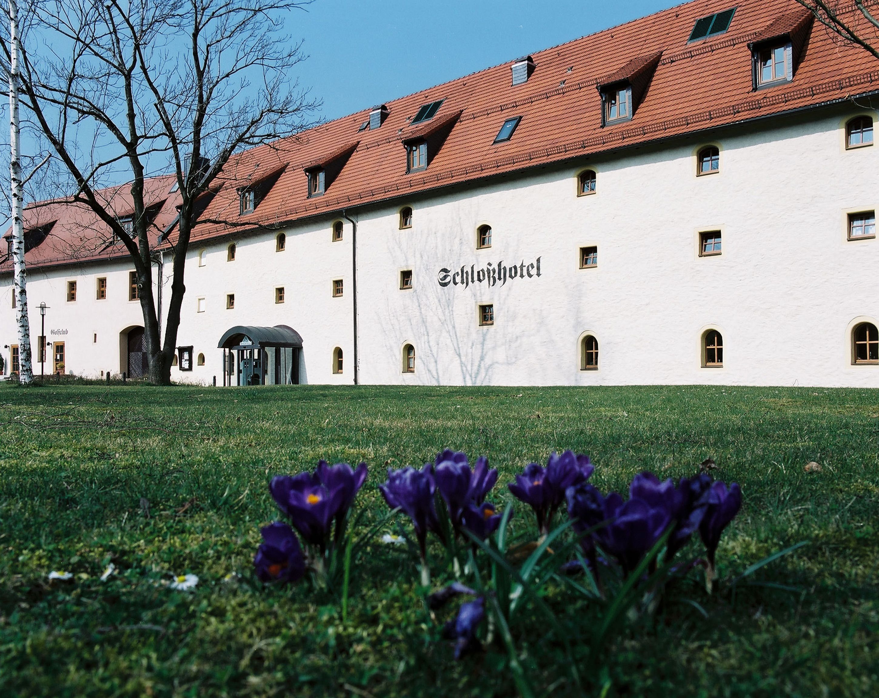 A building with a white facade and a red-tiled roof, labeled "Glößhotel."