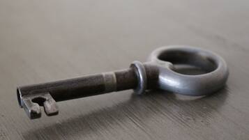 A close-up of a metal key with a worn handle on a wooden surface.
