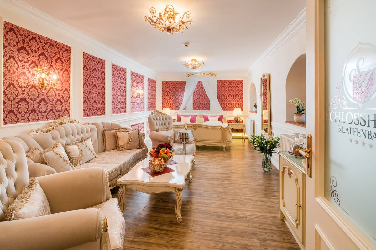 Une chambre luxueuse avec un grand canapé, une table basse agrémentée de fleurs, un miroir et un mur décoratif.