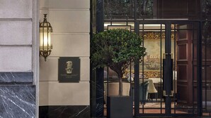 The entrance of The Ritz-Carlton Club with a marble facade, a lit wall lantern, and a potted tree. - The Ritz-Carlton, Kuala Lumpur (Kuala Lumpur)