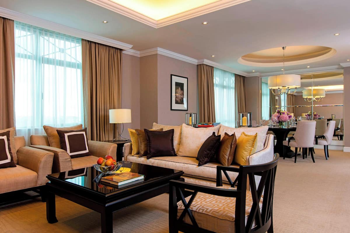 A spacious living room with a sofa, armchairs, a coffee table, and a dining area with a chandelier.