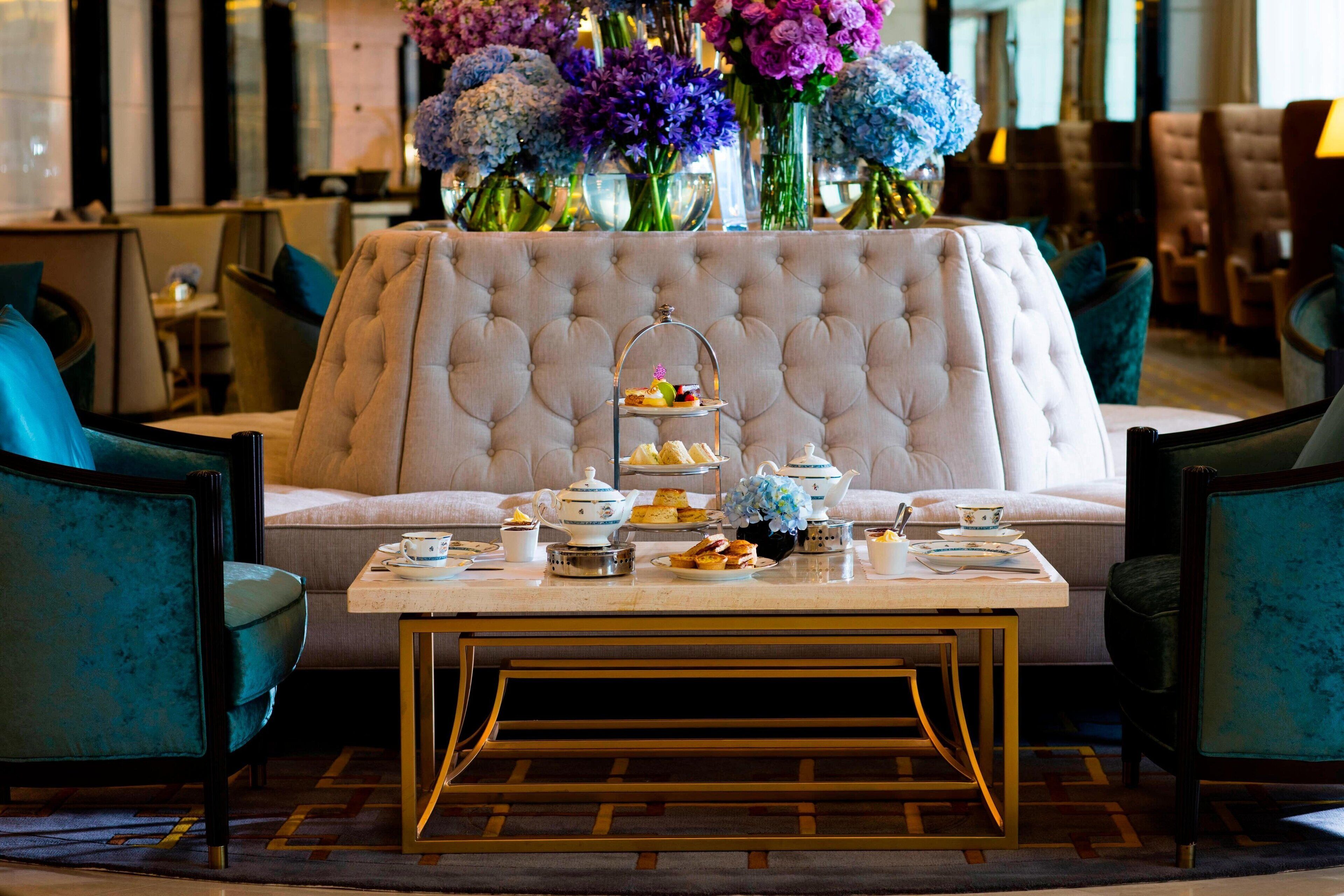 A luxurious seating area with a tufted sofa, a coffee table, and a floral arrangement.