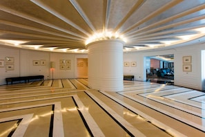 A spacious lobby with a high ceiling, a central column, and a patterned floor.