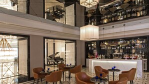 A spacious lobby with a piano, seating area, and a bar with a wine display. - The Ritz-Carlton, Kuala Lumpur (Kuala Lumpur)