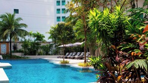A swimming pool with lounge chairs and tropical plants. - The Ritz-Carlton, Kuala Lumpur (Kuala Lumpur)