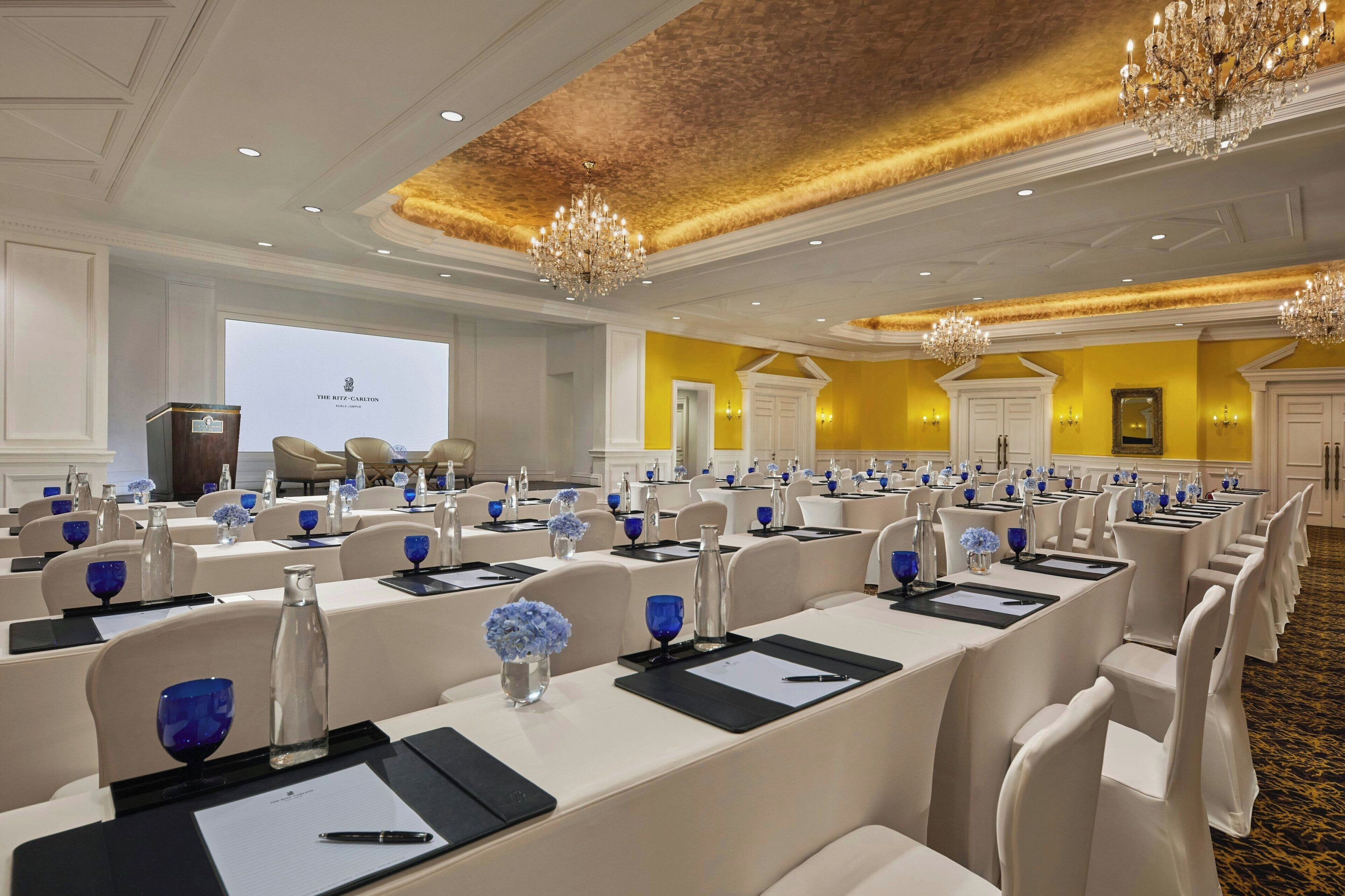 A conference room with rows of tables, chairs, and blue floral centerpieces.