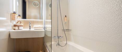 Une salle de bain moderne avec une douche à parois de verre, un lavabo avec des articles de toilette et un porte-serviettes.