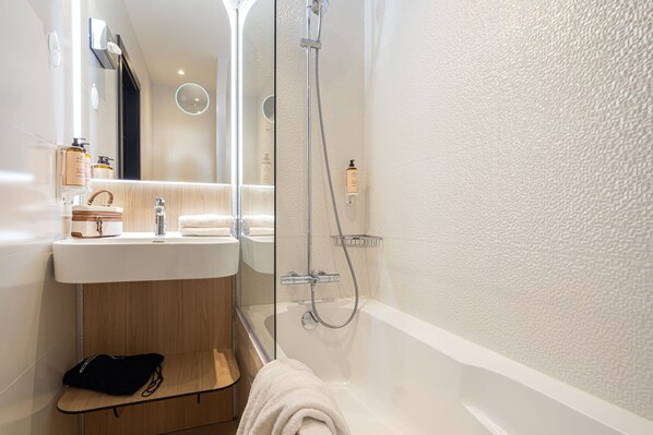 A modern bathroom with a glass-enclosed shower, a sink with toiletries, and a towel rack.