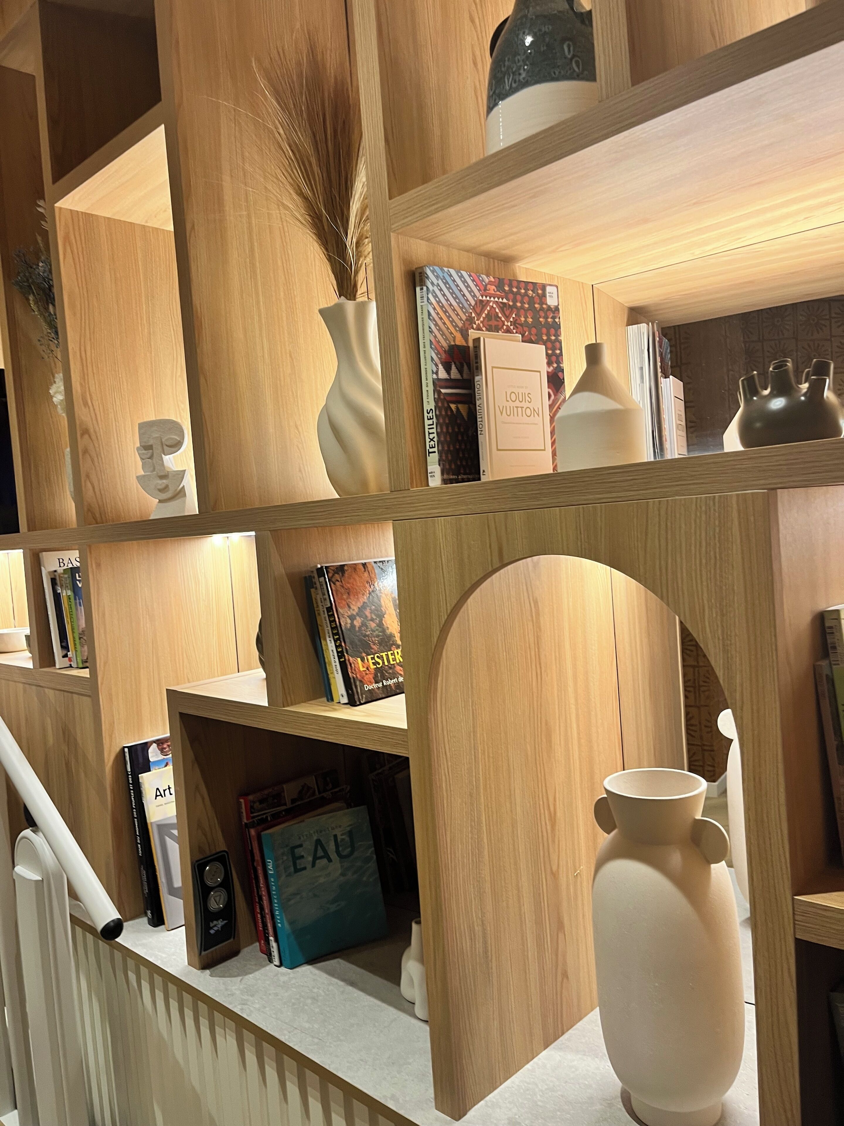 Ein Holzregal mit verschiedenen Büchern, einer Vase und Dekorationselementen.