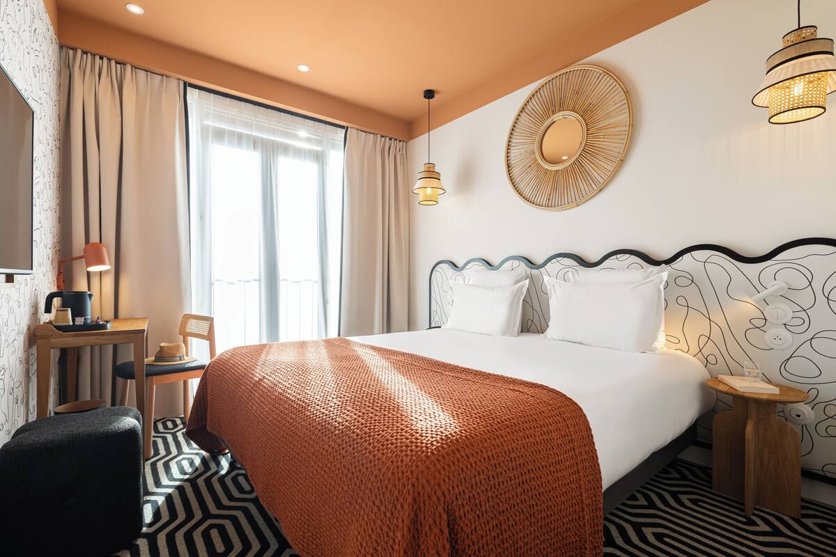 Une chambre d’hôtel avec un grand lit, un bureau avec une lampe, une chaise et une petite table avec une lampe.