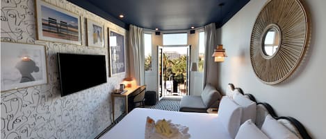 A hotel room with a large bed, a desk with a chair, a TV, and a view of the outdoors.