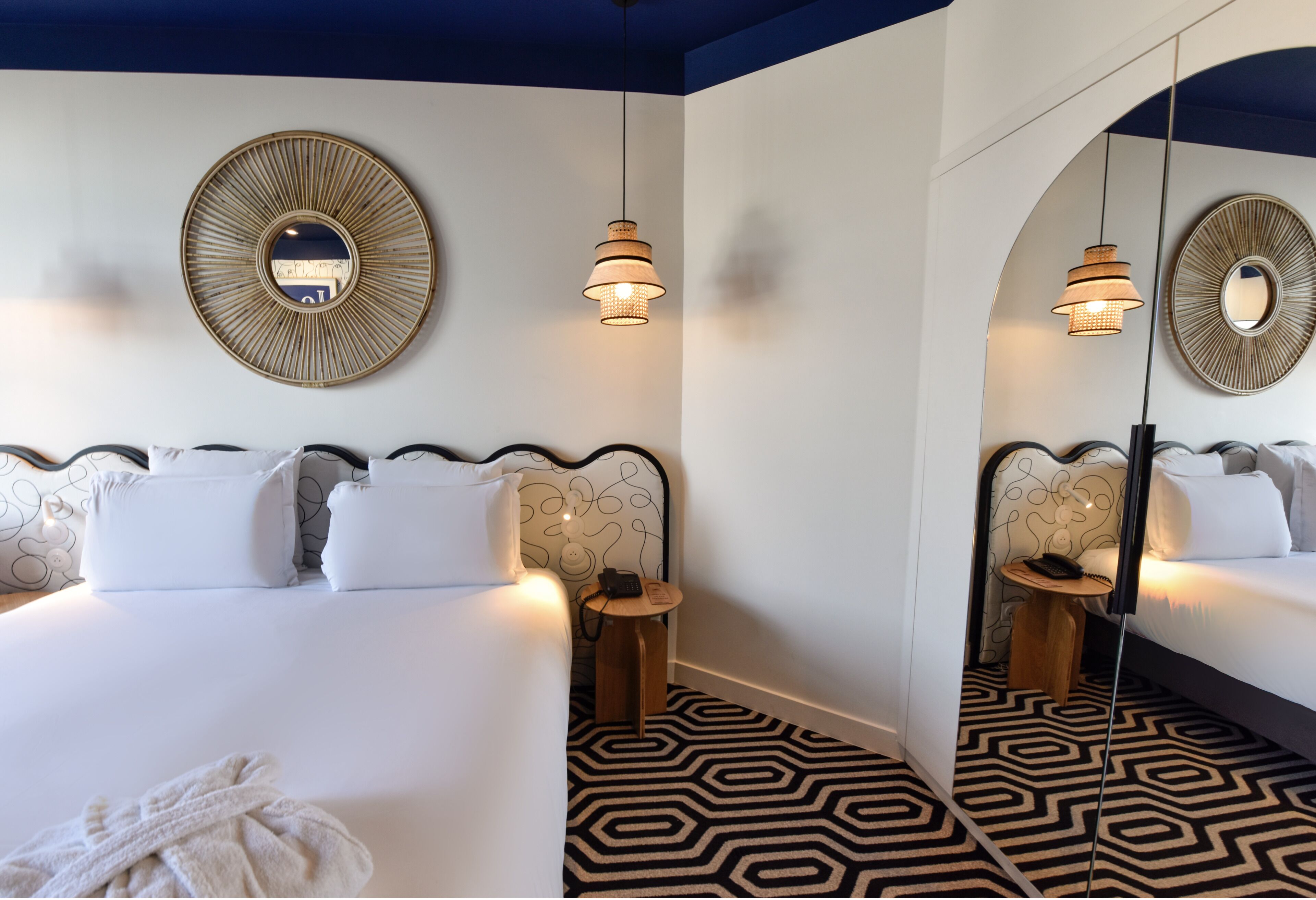 A hotel room with a large bed, two bedside tables, a mirror, and patterned floor.