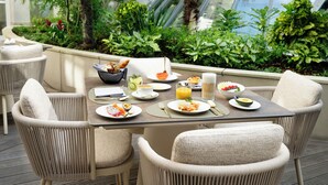 A dining area with wicker chairs and a table set for breakfast. - Conrad Hamburg (Hamburg)