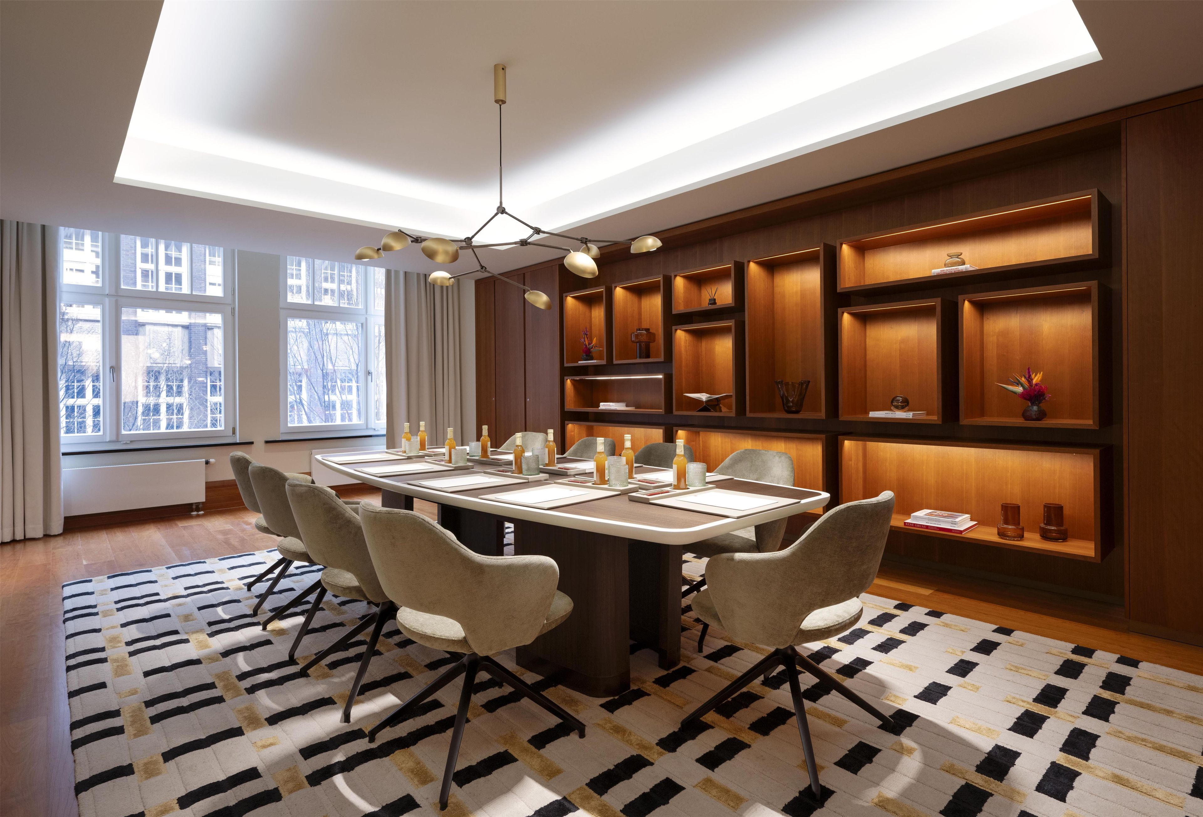 A modern conference room with a long table, chairs, and built-in shelving with decorative items.