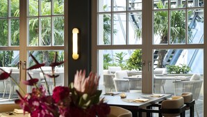 A restaurant with large windows, a vase of flowers, and a table set for dining. - Conrad Hamburg (Hamburg)