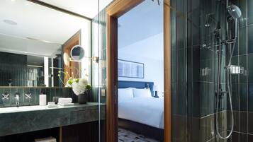 A modern bathroom with a glass shower enclosure, a large mirror, and a vanity with a marble countertop.